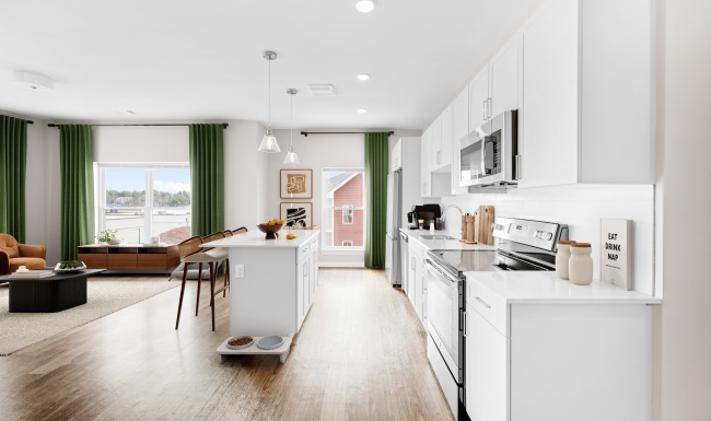 a kitchen with an island and open layout into the living room with large windows