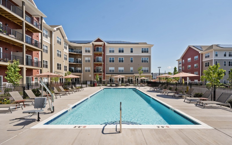 a swimming pool surrounded by lounge seating and shaded umbrellas 