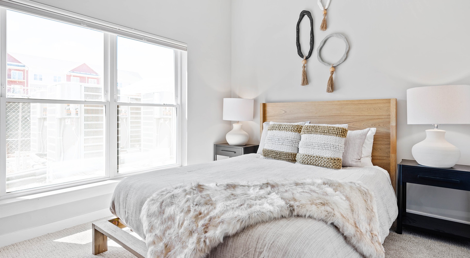 Relax and recharge in beautiful and spacious bedrooms Model bedroom at Millyard at Meadows Commons apartments in Newington, featuring carpeted flooring and windows with blinds.